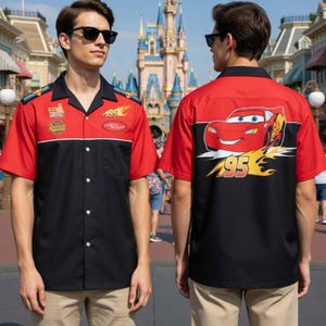 May include: A short-sleeved button-up shirt featuring a red and black color block design. The shirt has a collar and a front graphic with the text "195" and "Lightning McQueen". The back of the shirt features a large graphic of the character Lightning McQueen.