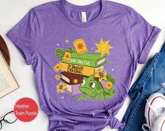 May include: Purple t-shirt with a graphic of a stack of books featuring a green chameleon and the text "Best Day Ever" and "The Snuggly Duckling".