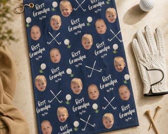 May include: A navy blue golf towel featuring a repeating pattern of a child's face, white golf balls, crossed golf clubs, and the text "Best Grandpa by Par". The towel includes a gold-toned metal grommet at the top corner for hanging.