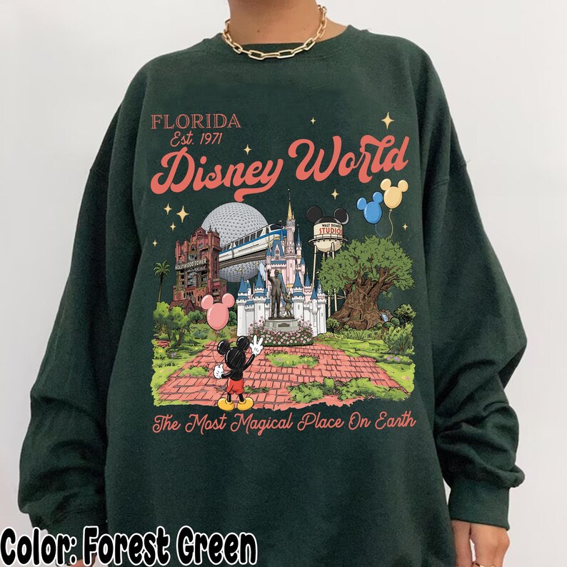 Puede incluir: Sudadera verde bosque con un dise&ntilde;o colorido de Disney World en Florida. El dise&ntilde;o incluye a Mickey Mouse, un castillo y el texto "Disney World" y "The Most Magical Place On Earth".