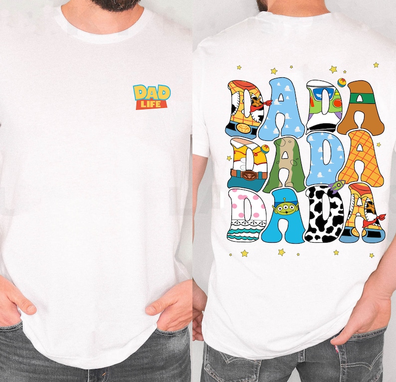 Op de afbeelding: Wit T-shirt met de tekst "DAD LIFE" op de voorkant en "DADA DADA DADA" op de achterkant. De tekst op de achterkant is in een kleurrijk, cartoonachtig lettertype met steraccenten. Een casual kledingstuk voor dagelijks gebruik.