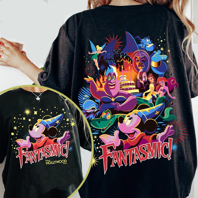 May include: Dark grey t-shirt with a vibrant graphic of Mickey Mouse in a wizard's hat, the word "Fantasmic!" in red, and other Disney characters. The design includes fireworks and the text "Hollywood".
