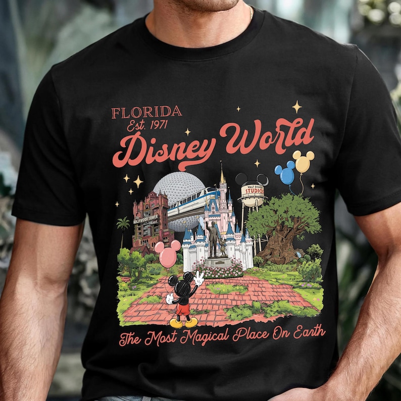 Puede incluir: Camiseta negra con un gr&aacute;fico colorido de Disney World. El dise&ntilde;o incluye el texto "Florida Est. 1971 Disney World" y una ilustraci&oacute;n de los puntos de referencia del parque, incluido Mickey Mouse. Tambi&eacute;n se incluye la frase "The Most Magical Place On Earth".