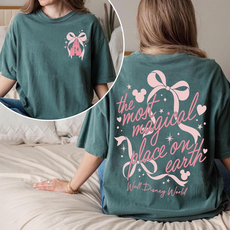 May include: Teal t-shirt with a pink castle and bow graphic on the front and the text "the most magical place on earth" on the back. The text includes Mickey Mouse silhouettes and stars.