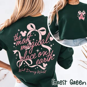 May include: Forest green sweatshirt with a pink bow and castle graphic. The back features the text "the most magical place on earth" with Mickey Mouse icons and the words "Walt Disney World".