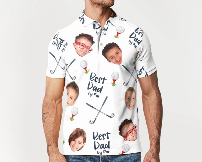 May include: White polo shirt with a repeating pattern of golf balls, golf clubs, and children's faces. The text "Best Dad by Par" is printed on the shirt. The shirt has a collared neckline and short sleeves.
