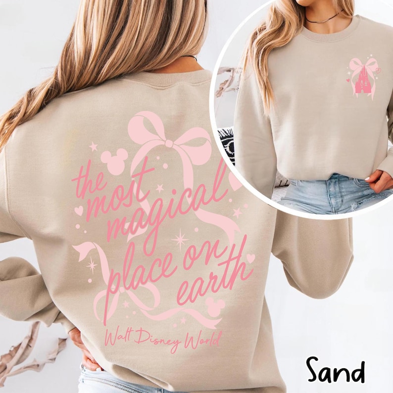 May include: Sand-colored sweatshirt with a pink bow and the text "the most magical place on earth" in a script font. The sweatshirt also features a small graphic of a bow and a castle. The words "Walt Disney World" are printed below.