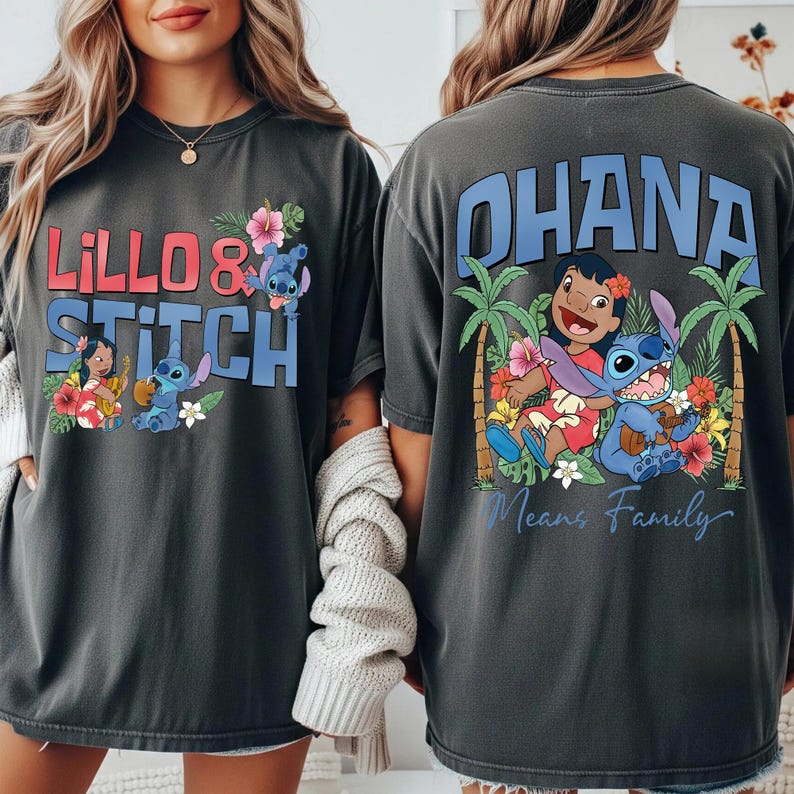 May include: Dark gray t-shirts featuring the characters Lilo and Stitch. The front of the shirt says "Lilo & Stitch" with images of the characters and flowers. The back of the shirt says "Ohana Means Family" with images of the characters and palm trees.