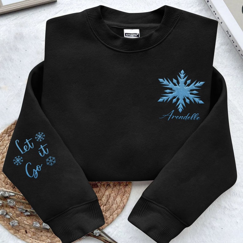 May include: Black sweatshirt with a blue snowflake and the text "Arendelle" embroidered on the front. The left sleeve has the text "Let it Go" and snowflakes embroidered on it.