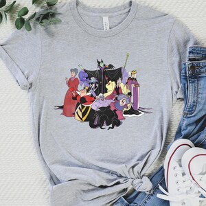 May include: A gray t-shirt with a graphic print of Disney villains, including Maleficent, Ursula, Cruella de Vil, and the Evil Queen. The villains are depicted in their iconic poses and outfits.