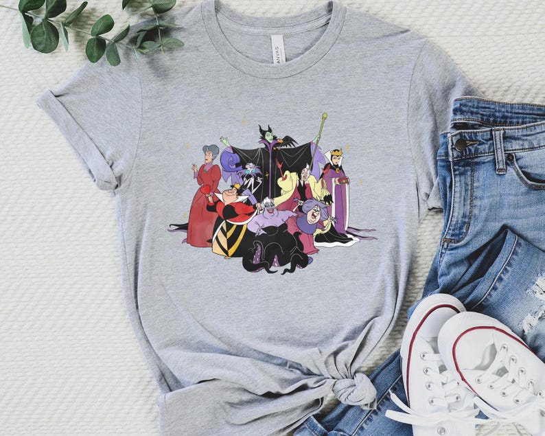 May include: A gray t-shirt with a graphic print of Disney villains, including Maleficent, Ursula, Cruella de Vil, and the Evil Queen. The villains are depicted in their iconic poses and outfits.