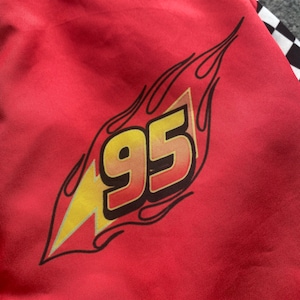 May include: Red jacket with a black and yellow lightning bolt and the number 95 in a flame design.
