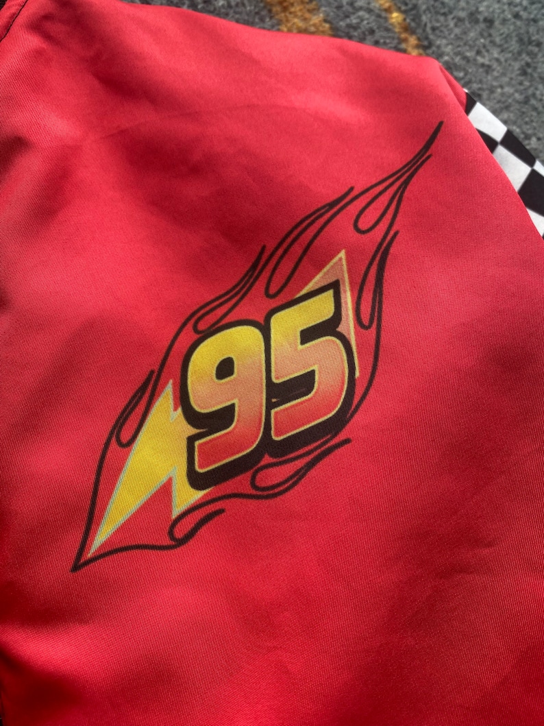 May include: Red jacket with a black and yellow lightning bolt and the number 95 in a flame design.