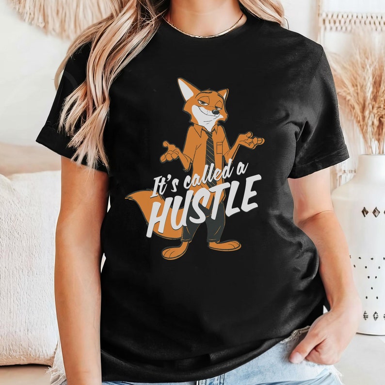May include: Black t-shirt featuring a cartoon fox wearing a tie and saying "It's called a hustle".