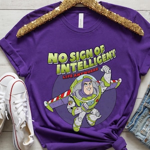 May include: Purple t-shirt with a cartoon image of Buzz Lightyear from Toy Story. The shirt has the text "No Sign of Intelligent Life Anywhere".