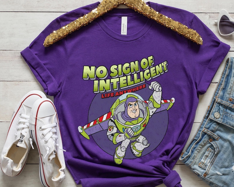 May include: Purple t-shirt with a cartoon image of Buzz Lightyear from Toy Story. The shirt has the text "No Sign of Intelligent Life Anywhere".