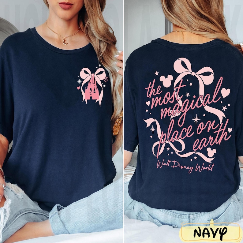 May include: Navy blue t-shirt with a pink castle and bow graphic on the front. The back of the shirt features the text "the most magical place on earth" with a bow and Walt Disney World text. The word "NAVY" is at the bottom.