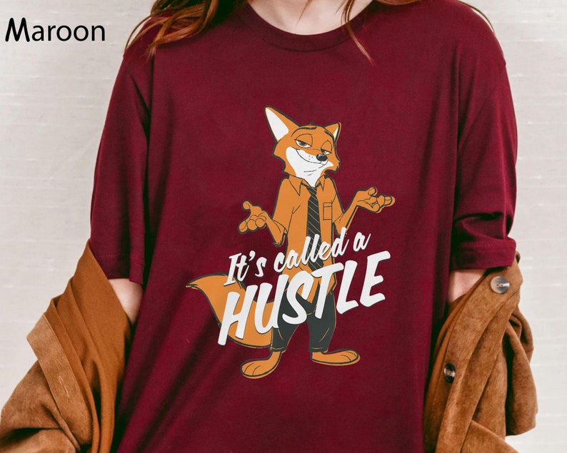 May include: A maroon t-shirt with a cartoon fox wearing a tie and the text "It's called a hustle".
