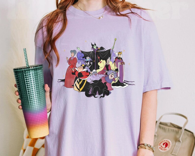 May include: A purple t-shirt with a graphic print of Disney villains, including Maleficent, Ursula, Cruella de Vil, and the Evil Queen. The villains are depicted in a group, with Maleficent in the center.