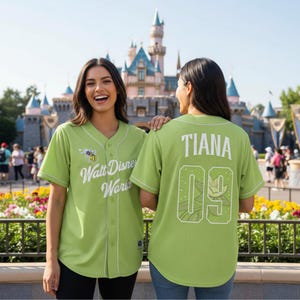 May include: Lime green baseball jersey with white trim and the text "Walt Disney World" on the front. The back of the jersey has the name "TIANA" and the number "09". A cartoon bee graphic is also visible.