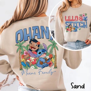 May include: Sand-colored sweatshirt featuring a graphic of Lilo and Stitch with the text "OHANA Means Family." The design includes palm trees, flowers, and the characters Lilo and Stitch. A smaller image shows the text "Lillo & Stitch."