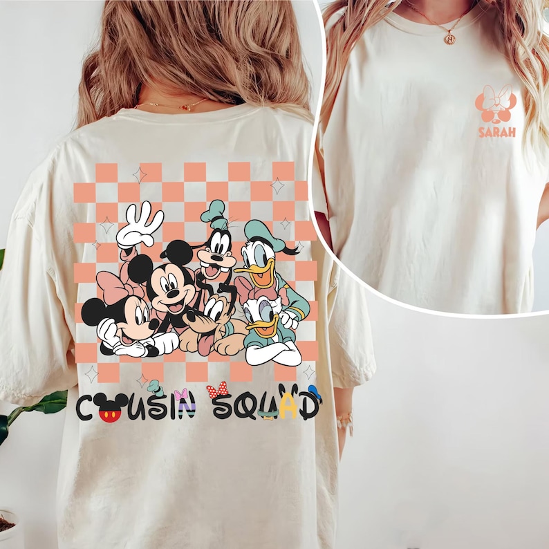 May include: A cream-coloured t-shirt with a graphic of Disney characters, including Mickey and Minnie Mouse, Goofy, and Donald Duck, with the text "Cousin Squad." A smaller graphic with the name "Sarah" is on the front.
