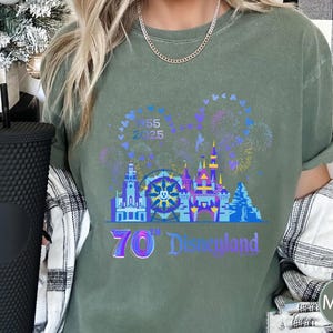 May include: A green t-shirt with a graphic of a castle, fireworks, and a Ferris wheel. The text "70th Disneyland" is printed on the shirt.