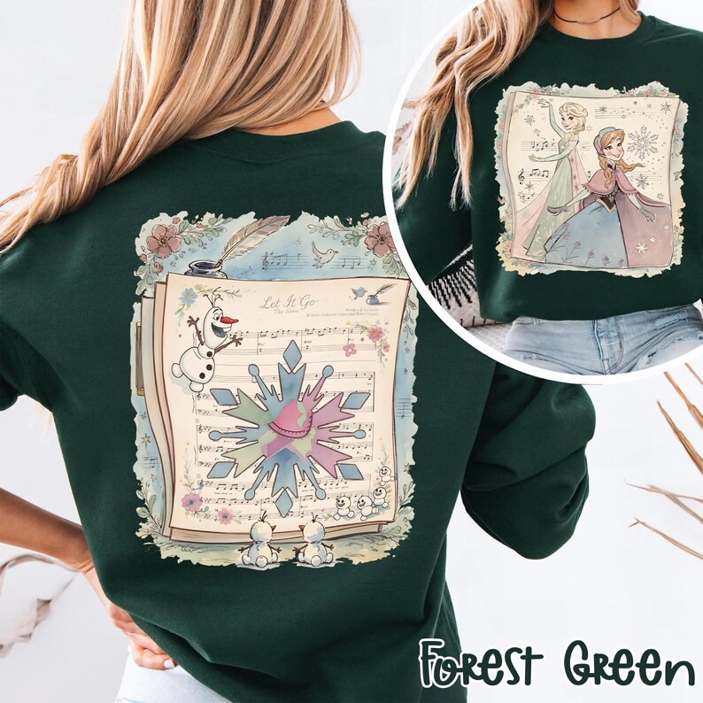 May include: Forest green sweatshirt featuring a colorful graphic of a musical score with the words "Let It Go", snowflakes, and cartoon characters. The sweatshirt also has a smaller image of two cartoon characters. The text "Forest Green" is at the bottom.
