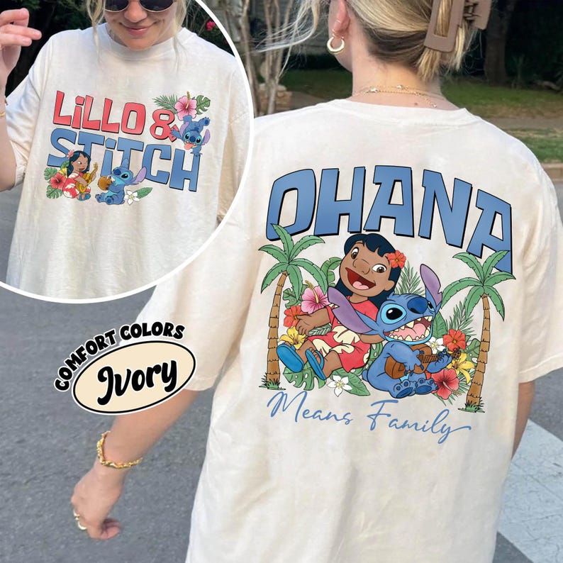 May include: Ivory-colored t-shirt featuring the text "Lillo & Stitch" in red and blue, with cartoon characters and floral accents. The back of the shirt displays "Ohana Means Family" with a graphic of Lilo and Stitch. The shirt is a Comfort Colors brand.