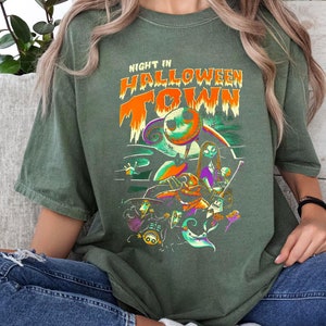 Może przedstawiać: Zielona koszulka z nadrukiem graficznym postaci z filmu "Koszmar przed świętami". Na koszulce widnieje napis "Night in Halloween Town".
