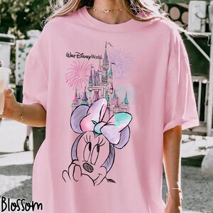 Pode incluir: Camiseta rosa claro com um desenho da Minnie Mouse, um castelo e fogos de artif&iacute;cio. O texto "Walt Disney World" est&aacute; acima do castelo. A palavra "Blossom" est&aacute; na parte inferior esquerda.