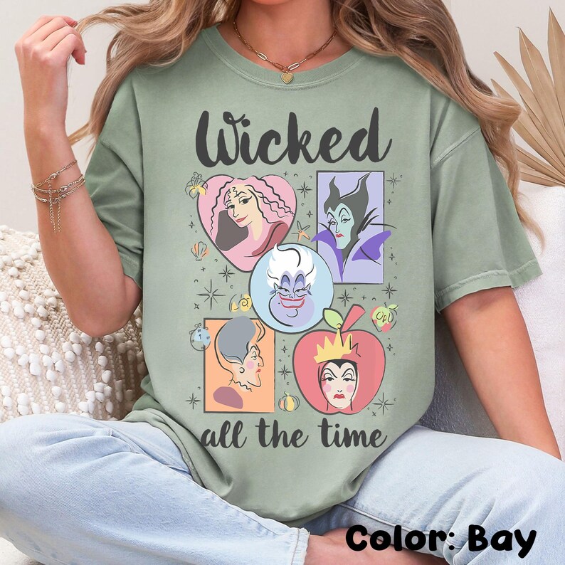K&ouml;nnte beinhalten: Bay-gr&uuml;nes T-Shirt mit dem Text "Wicked all the time". Das Shirt zeigt Cartoon-Portr&auml;ts von Disney-B&ouml;sewichten in Herz- und Quadratformen. Die Farbe des Shirts ist Bay.