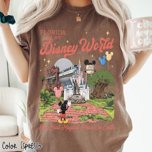 Puede incluir: Camiseta color espresso con un dise&ntilde;o de Disney World. El dise&ntilde;o incluye el texto "Florida Est. 1971" y "Disney World" en una fuente retro, junto con ilustraciones de lugares emblem&aacute;ticos del parque y Mickey Mouse. Tambi&eacute;n incluye la frase "The Most Magical Place On Earth".