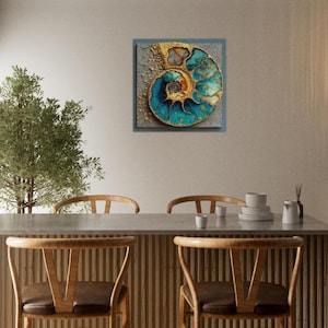 May include: Square wall art featuring a detailed, abstract depiction of a nautilus shell. The artwork showcases a spiral design with teal and gold accents against a textured gray background. The piece is framed and mounted on a neutral-colored wall.