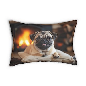 May include: A brown and white pug dog laying on a tan pillow in front of a fireplace. The dog is looking directly at the camera with its tongue sticking out.