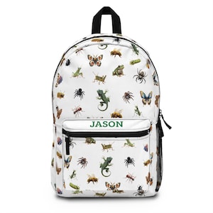 Puede incluir: Mochila blanca con un estampado de varios insectos, incluyendo mariposas, arañas y lagartos. La mochila tiene un asa superior negra, cremalleras negras y un bolsillo frontal con el nombre "JASON" en verde.