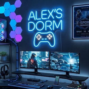 May include: A blue neon sign displaying the text ALEX'S DORM above a gaming controller icon. The sign is mounted on a dark wall above two computer monitors, surrounded by hexagonal wall lights and a framed e-sports tournament poster.