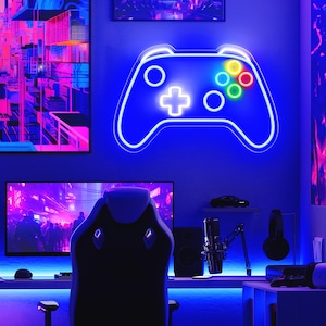 May include: A neon blue gaming controller light fixture with colorful buttons hangs on a blue wall. A gaming setup includes a monitor, chair, microphone, and headphones. The room is illuminated with blue LED lights.