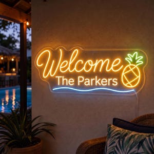 Könnte beinhalten: Ein rechteckiges Neonschild an einer Wand mit dem gelben Schriftzug Welcome, dem weißen Text The Parkers und einer gelben Ananasgrafik. Eine dünne blaue horizontale Linie unterstreicht den Text, alles leuchtet auf einer strukturierten Wand.