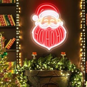 May include: A red neon sign in the shape of Santa Claus with the words "HO HO HO" in the beard. The sign is mounted on a brown wall, with a fireplace mantel decorated with greenery and candles below. String lights are on either side.