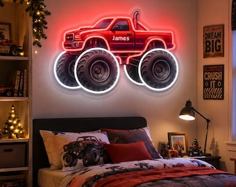 Pode incluir: Um letreiro de néon vermelho em forma de monster truck com pneus pretos grandes e um contorno branco brilhante. A carroçaria do camião apresenta o nome James em letras brancas. O letreiro está montado numa parede acima de uma cama.