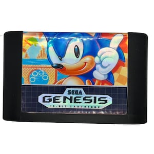 May include: A Sega Genesis game cartridge featuring a blue and red cartoon character with a white background. The cartridge is black with the text "SEGA GENESIS 16-BIT CARTRIDGE" printed on it.