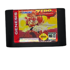 May include: A Sega Genesis game cartridge for the game "7 Zero: The Kamikaze Squirrel" by Sunsoft. The cartridge is red and black with a picture of a cartoon squirrel holding a throwing star. The game is rated MA-13 by the V.R.C.