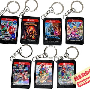 May include: Eight black plastic keychains shaped like Nintendo Switch game cartridges. Each keychain features a different Nintendo Switch game cover art, including Super Mario Bros. Wonder, Minecraft Dungeons, Minecraft Legends, Princess Peach: Showtime, Mario Kart 8 Deluxe, Super Mario 3D World + Bowser's Fury, and Mario Party Superstars.