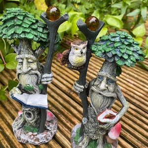 Pu&ograve; includere: Due statue da giardino fantasiose raffiguranti figure simili ad alberi con lunghe barbe, che tengono bastoni sormontati da globi color ambra. Una figura tiene in mano un libro. Un gufo &egrave; appollaiato su un bastone. Le statue hanno un fogliame verde.