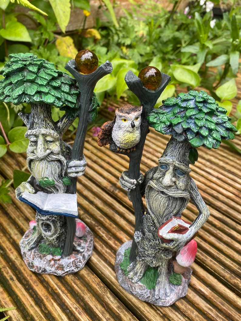 Pu&ograve; includere: Due statue da giardino fantasiose raffiguranti figure simili ad alberi con lunghe barbe, che tengono bastoni sormontati da globi color ambra. Una figura tiene in mano un libro. Un gufo &egrave; appollaiato su un bastone. Le statue hanno un fogliame verde.