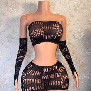 May include: Black lingerie set with a strapless top and a mini skirt. Both pieces feature a geometric pattern with small holes.