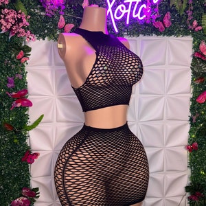 May include: Black mesh crop top and skirt set. The top has a high neckline and the skirt is a mini length. Both pieces are made of a stretchy, see-through mesh fabric.