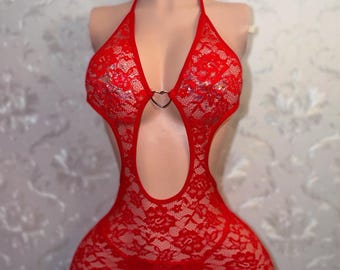Può includere: Un body in pizzo rosso con collo all'americana e un accento a forma di cuore. Il design a schiena scoperta presenta uno scollo a goccia e un perizoma abbinato. La lingerie è esposta su un manichino.