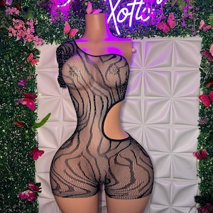 Könnte beinhalten: Schwarzer One-Shoulder-Bodysuit mit Zebra-Muster und Strasssteinen. Der Bodysuit hat einen Ausschnitt an der Seite.